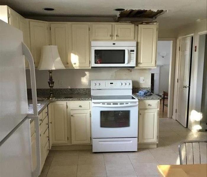 Kitchen with cream cabinets and a section of drywall removed from the ceiling