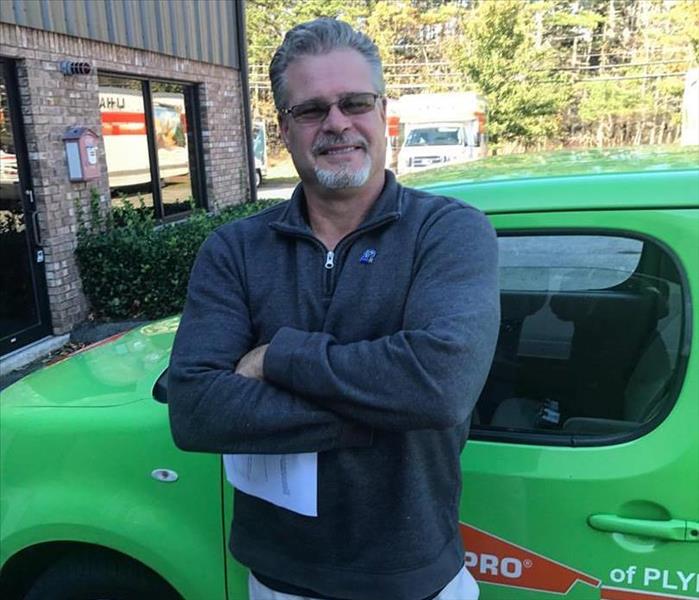 male employee standing in front of a green SERVPRO car
